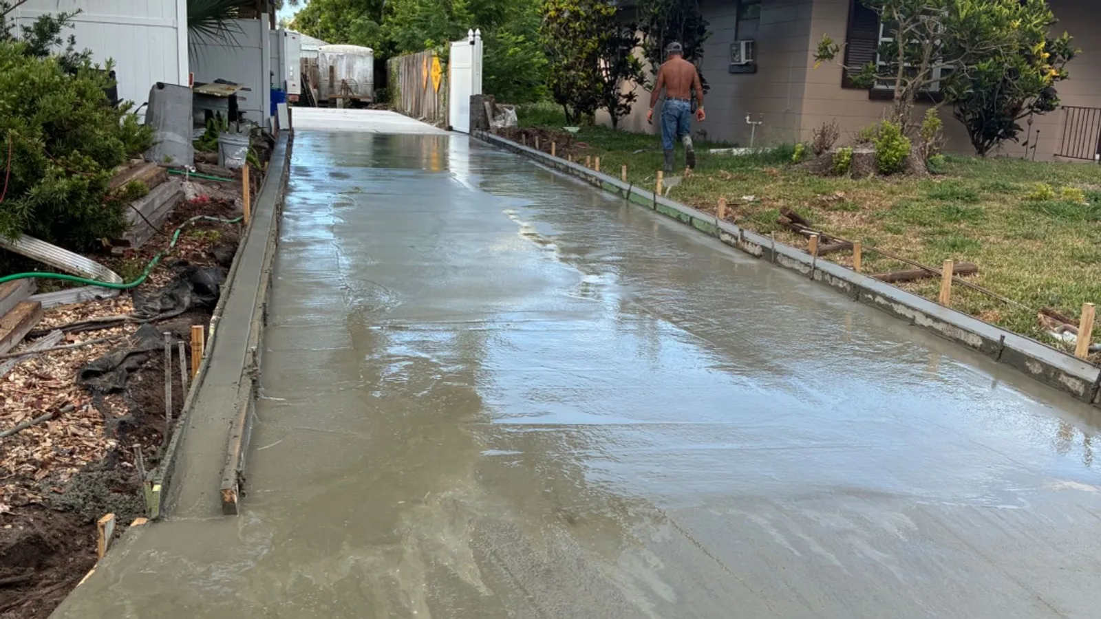 A long driveway freshly poured and still wet, the crew working at the far end